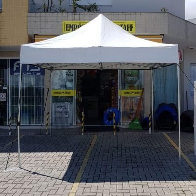 Tenda sanfonada branca montada na frente de uma loja